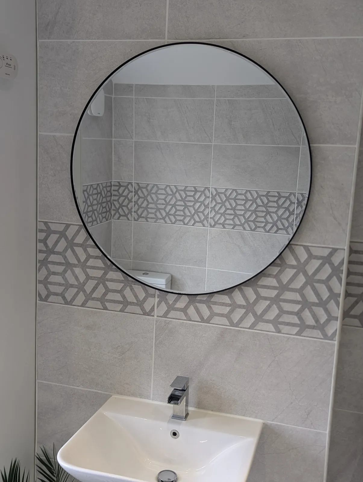 Round bathroom mirror hung above a sink