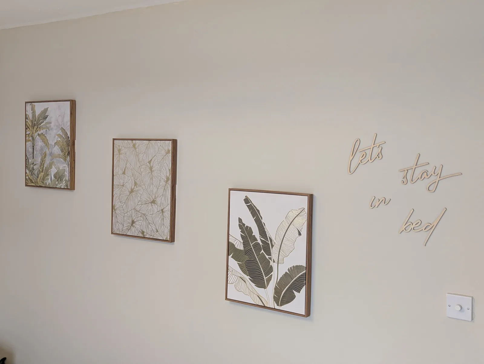 Framed prints and wall lettering hung in a bedroom